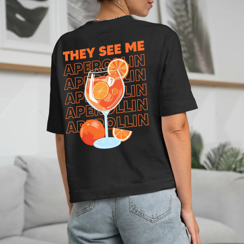 schwarzes Frauen T-Shirt Rückenprint mit "They see me aperolin" personalisiertesm Spruch als Sommer Geschenkidee von Love & Faith